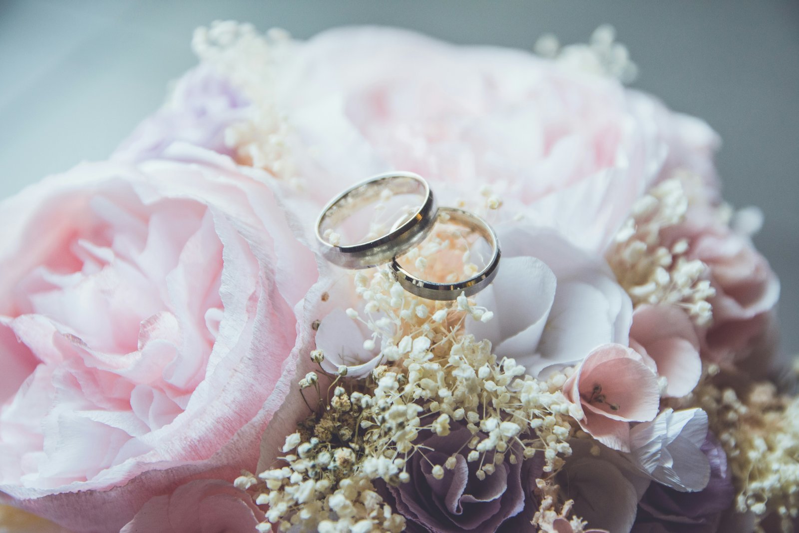 Two wedding rings resting on a bouquet of soft pink flowers
